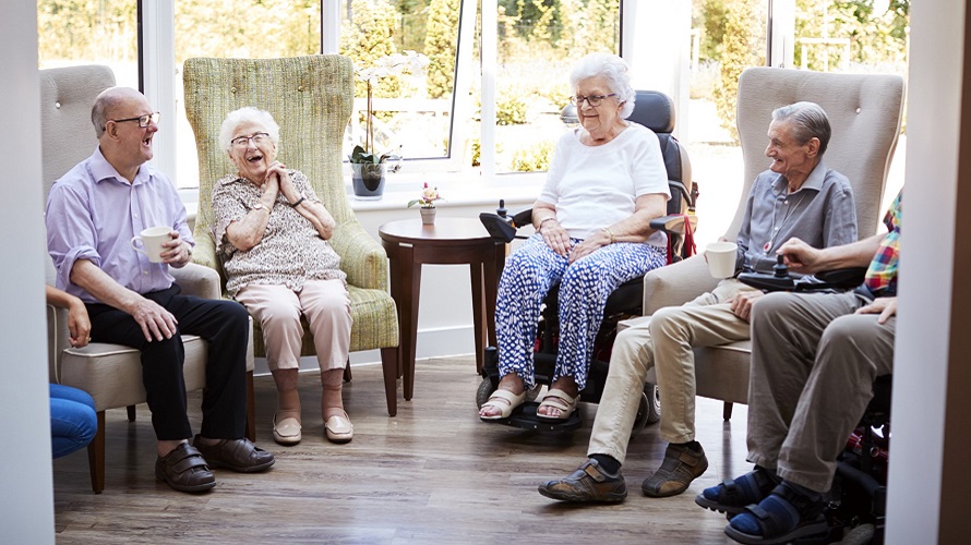 Fünf Senioren sitzen in einem Stuhlkreis und lachen Fünf Senioren sitzen in einem Stuhlkreis und lachen